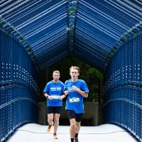 Individuals in blue shirts running through little mac bridge